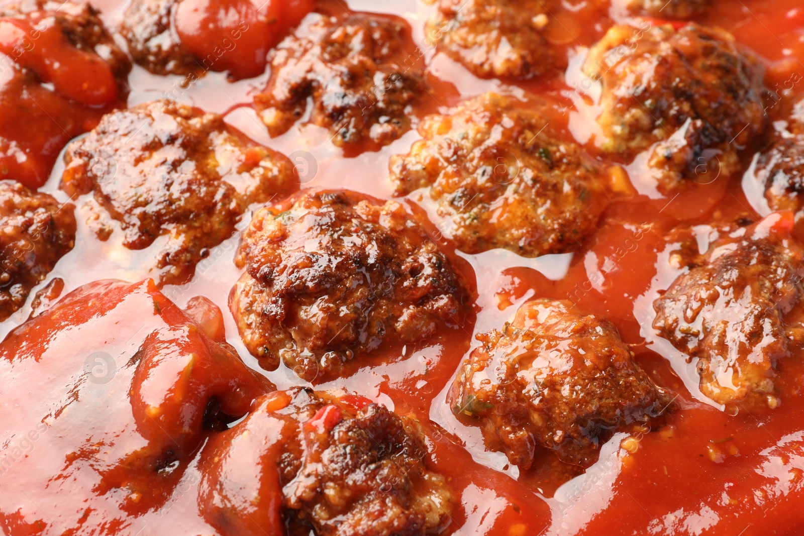 Photo of Delicious meatballs with tomato sauce as background, closeup