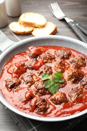 Photo of Delicious meatballs with tomato sauce in frying pan on table, closeup