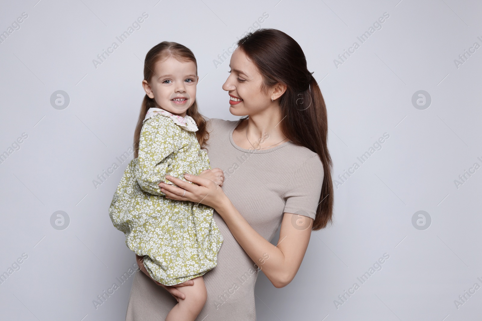 Photo of Happy mother with her cute little daughter on grey background