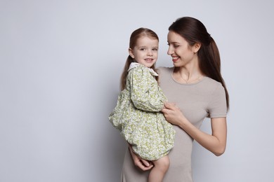 Happy mother with her cute little daughter on grey background, space for text