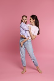 Photo of Happy mother with her cute little daughter on pink background