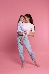 Happy mother with her cute little daughter on pink background