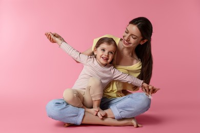 Happy mother with her cute little daughter on pink background