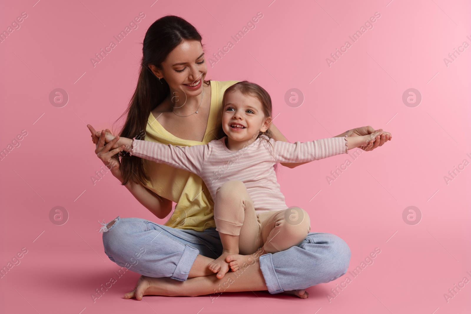 Photo of Happy mother with her cute little daughter on pink background