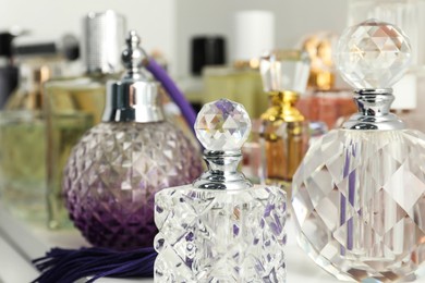 Photo of Different aromatic perfumes in bottles on light shelf, closeup