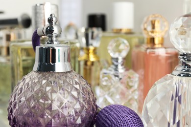 Photo of Different aromatic perfumes in bottles on light background, closeup