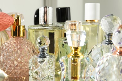 Different aromatic perfumes in bottles on mirror surface, closeup