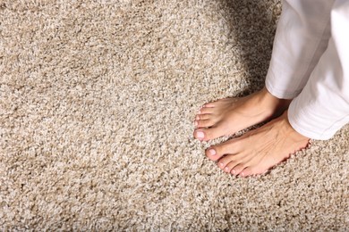 Photo of Woman on soft beige carpet indoors, above view. Space for text