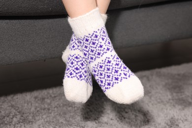 Photo of Little child wearing socks above soft grey carpet indoors, closeup