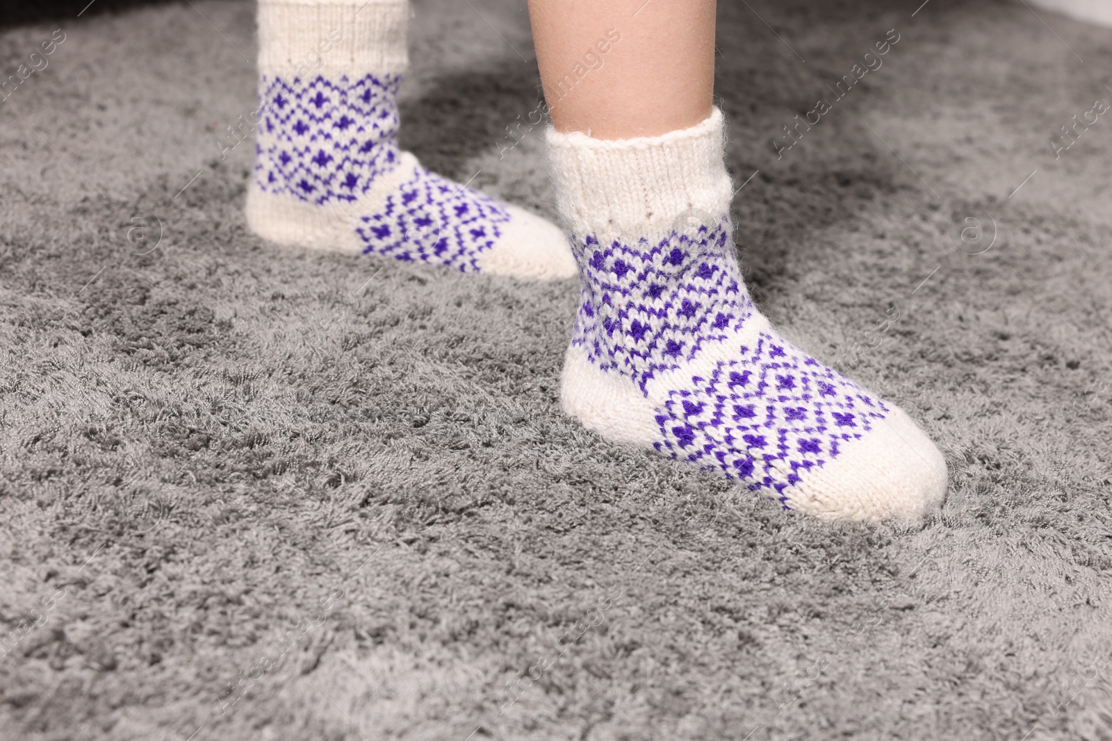 Little child wearing socks on soft grey carpet indoors, closeup Photo of Little child wearing socks on soft grey carpet indoors, closeup