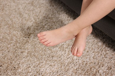 Photo of Little child above soft beige carpet indoors, closeup. Space for text