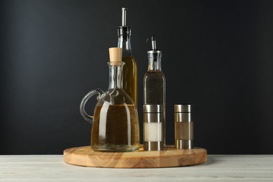 Photo of Salad dressings and spices on white wooden table against black background