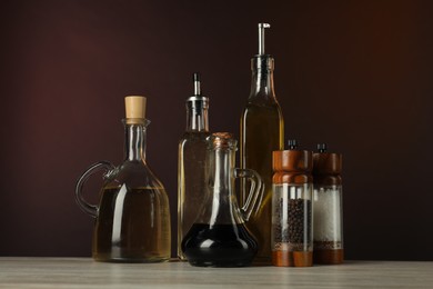 Photo of Salad dressings and spices on wooden table against dark background