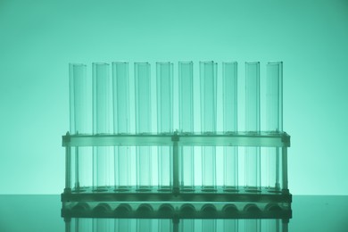 Photo of Empty test tubes on mirror surface against green background. Laboratory glassware