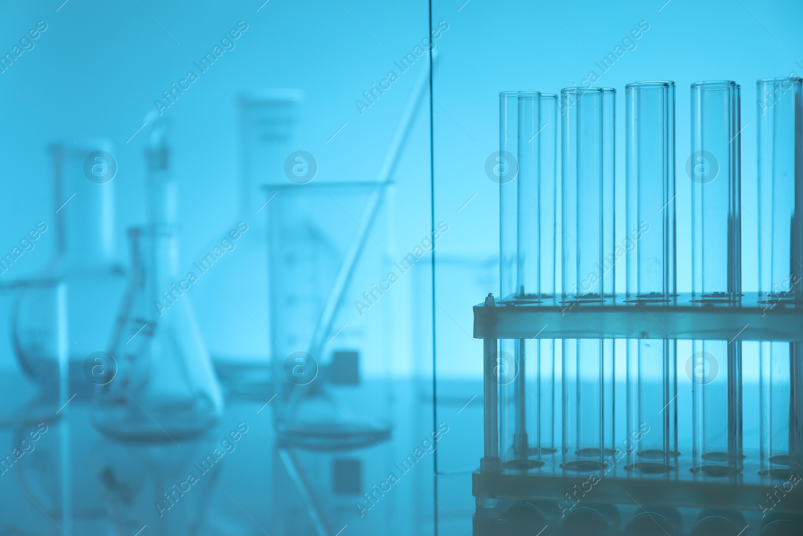 Photo of Laboratory glassware on mirror surface against light blue background