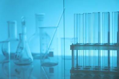 Photo of Laboratory glassware on mirror surface against light blue background