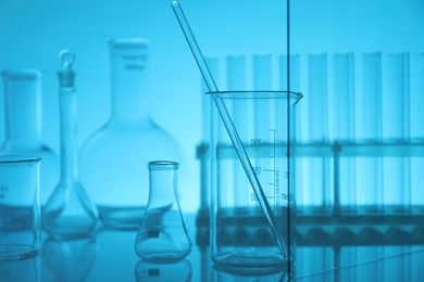 Photo of Laboratory glassware on mirror surface against light blue background