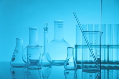 Photo of Laboratory glassware on mirror surface against light blue background