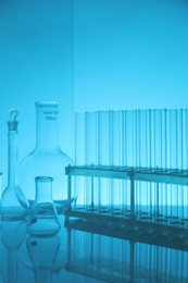 Photo of Laboratory glassware on mirror surface against light blue background