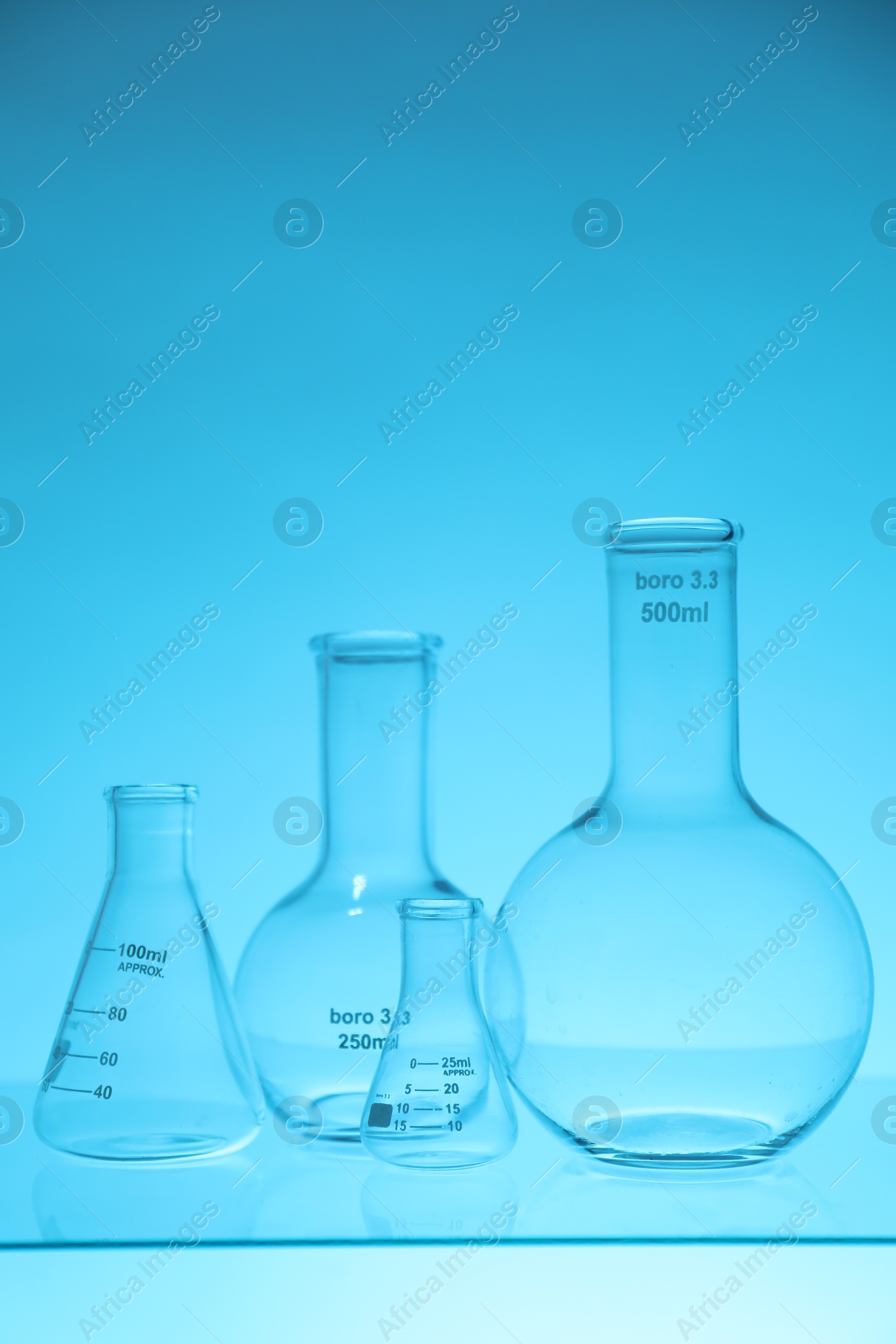 Photo of Empty flasks on light blue background. Laboratory equipment