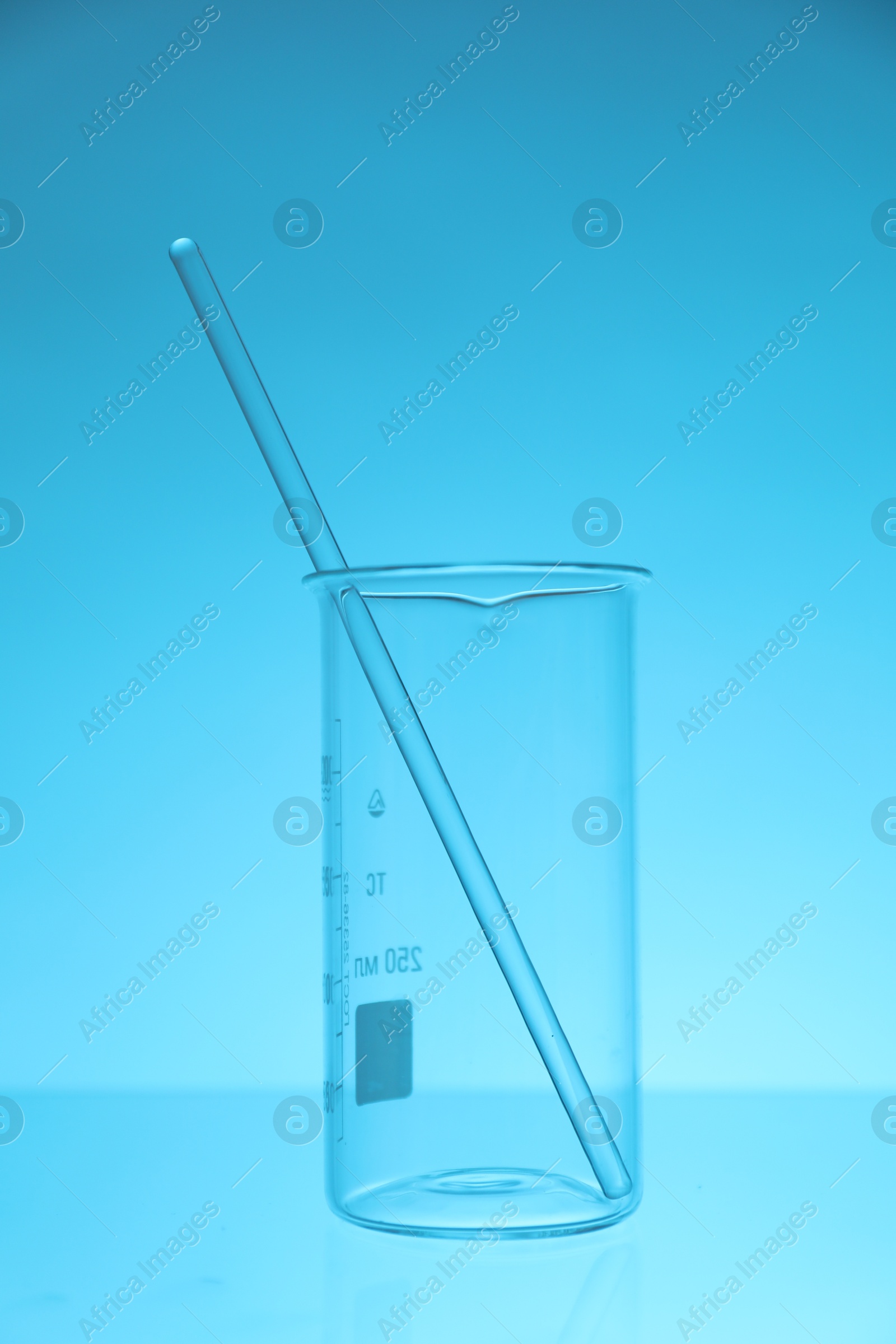 Photo of Beaker and rod on light blue background. Laboratory equipment