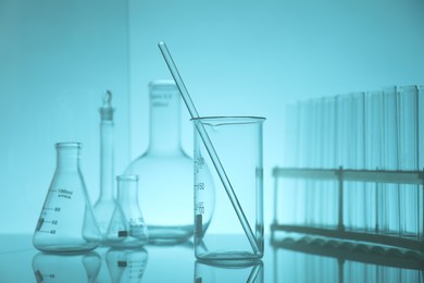 Photo of Laboratory glassware on mirror surface against light blue background