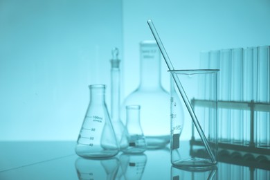 Photo of Laboratory glassware on mirror surface against light blue background