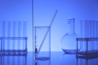 Photo of Laboratory glassware on mirror surface against blue background