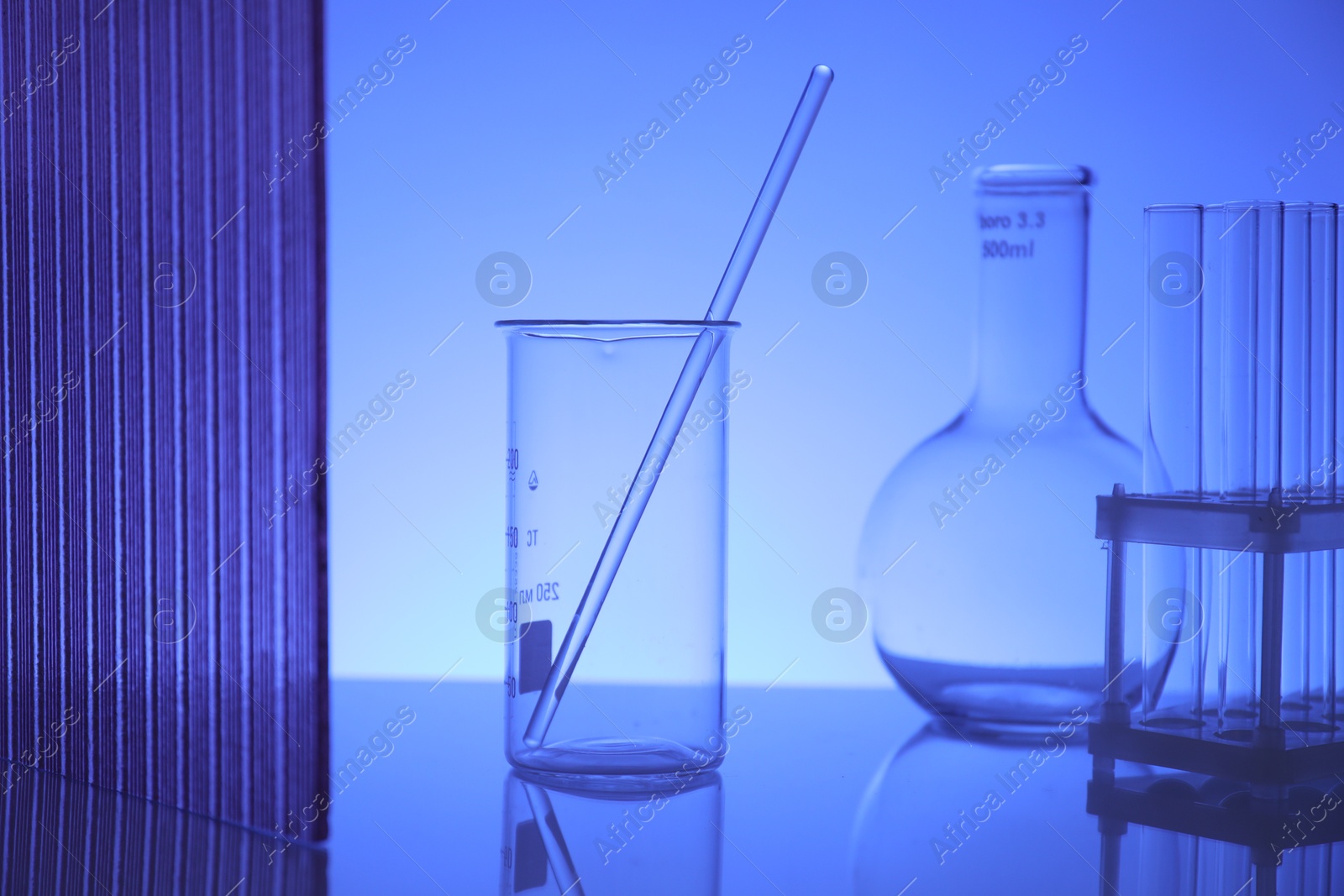 Photo of Laboratory glassware on mirror surface against blue background