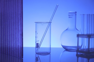 Photo of Laboratory glassware on mirror surface against blue background