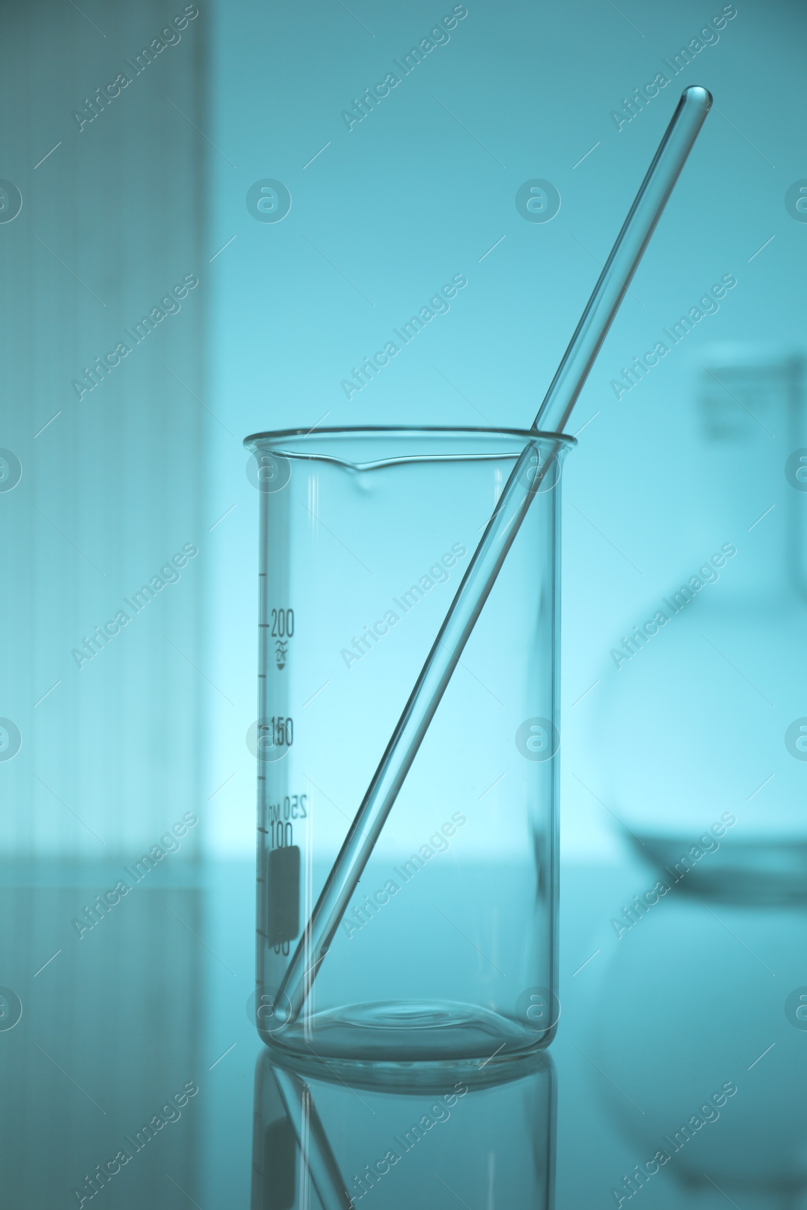 Photo of Beaker and rod on light blue background. Laboratory equipment