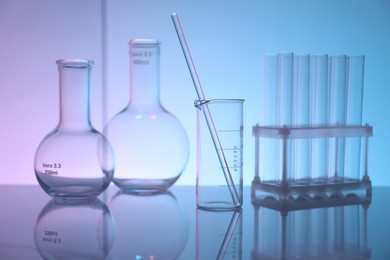 Photo of Laboratory glassware on mirror surface against color background