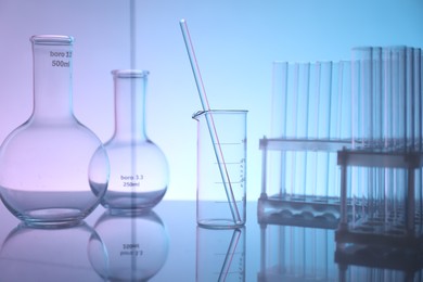 Photo of Laboratory glassware on mirror surface against color background