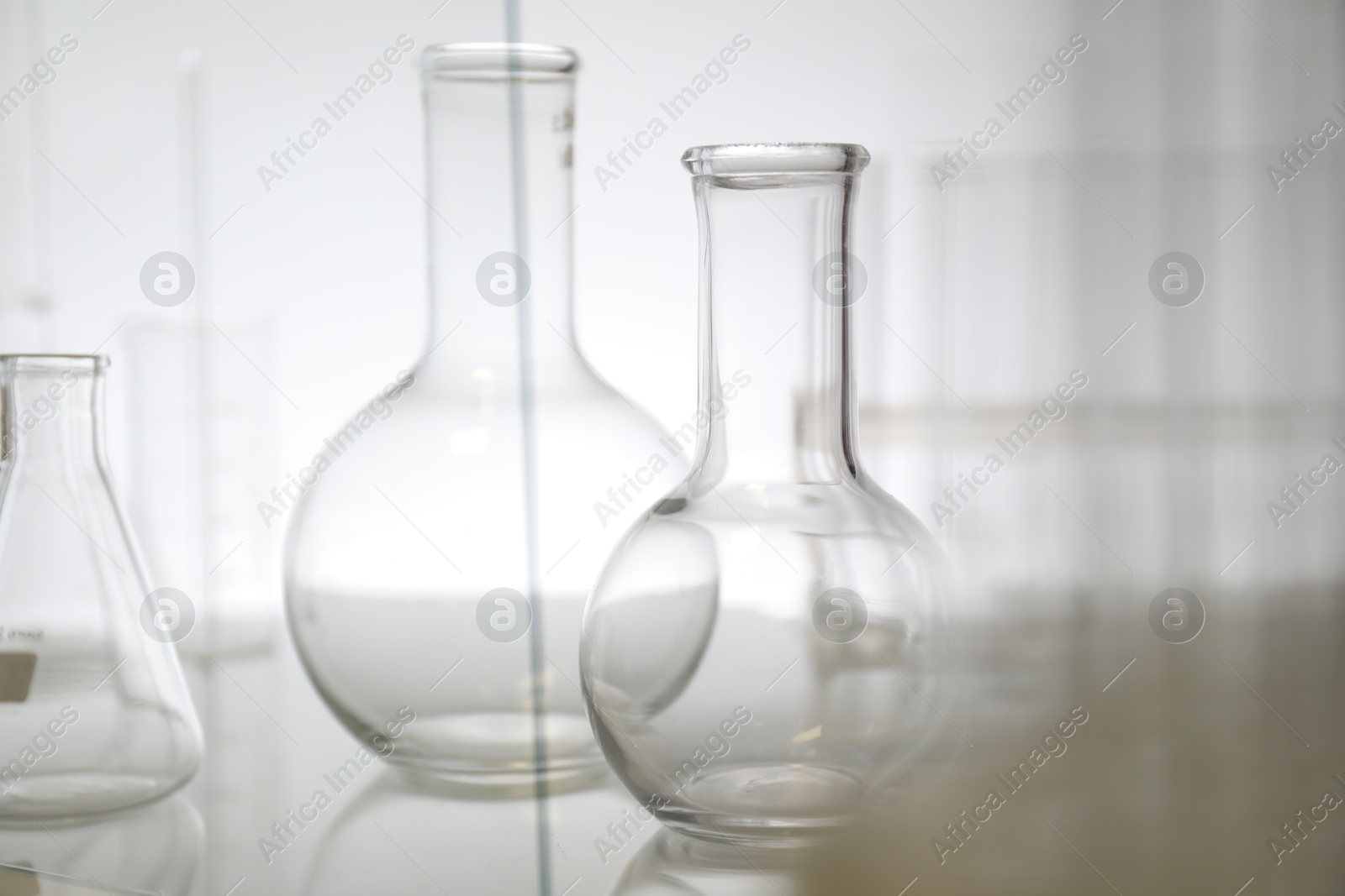 Photo of Empty flasks on light background. Laboratory equipment