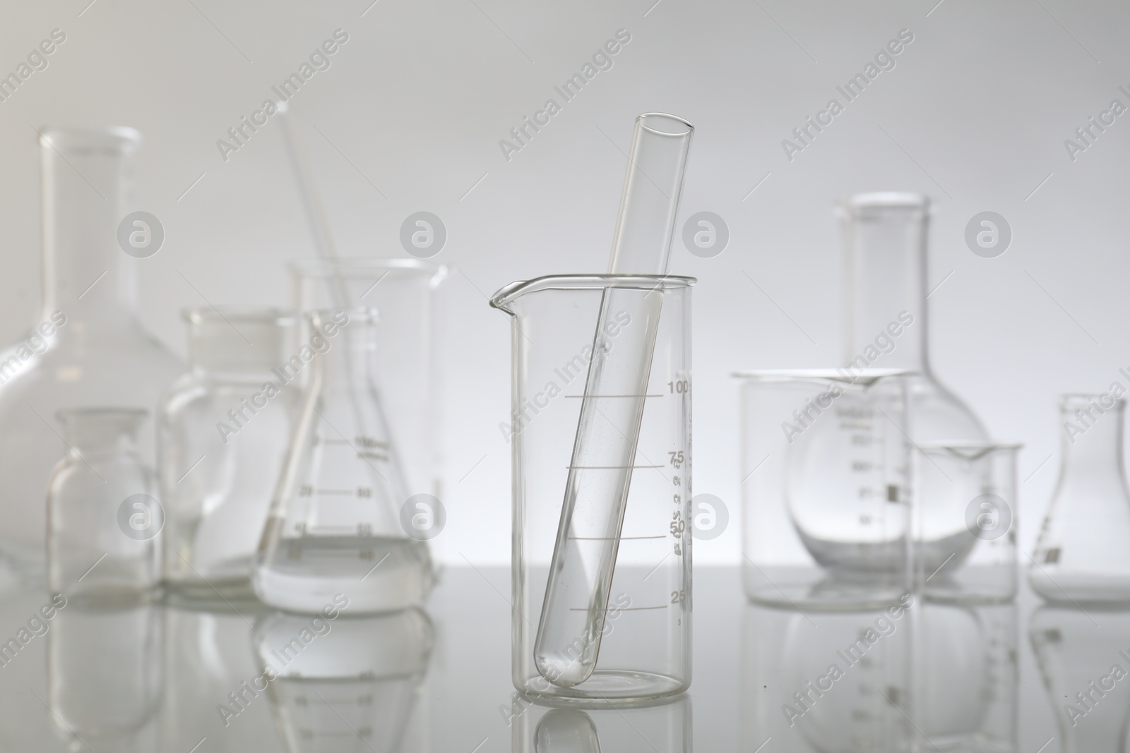 Photo of Laboratory glassware on mirror surface against light background