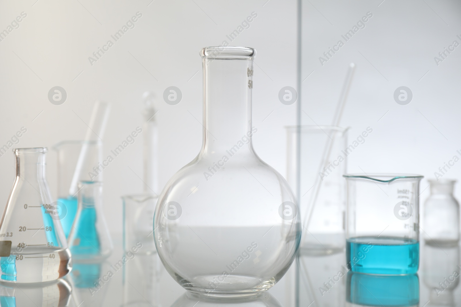 Photo of Laboratory glassware on mirror surface against light background