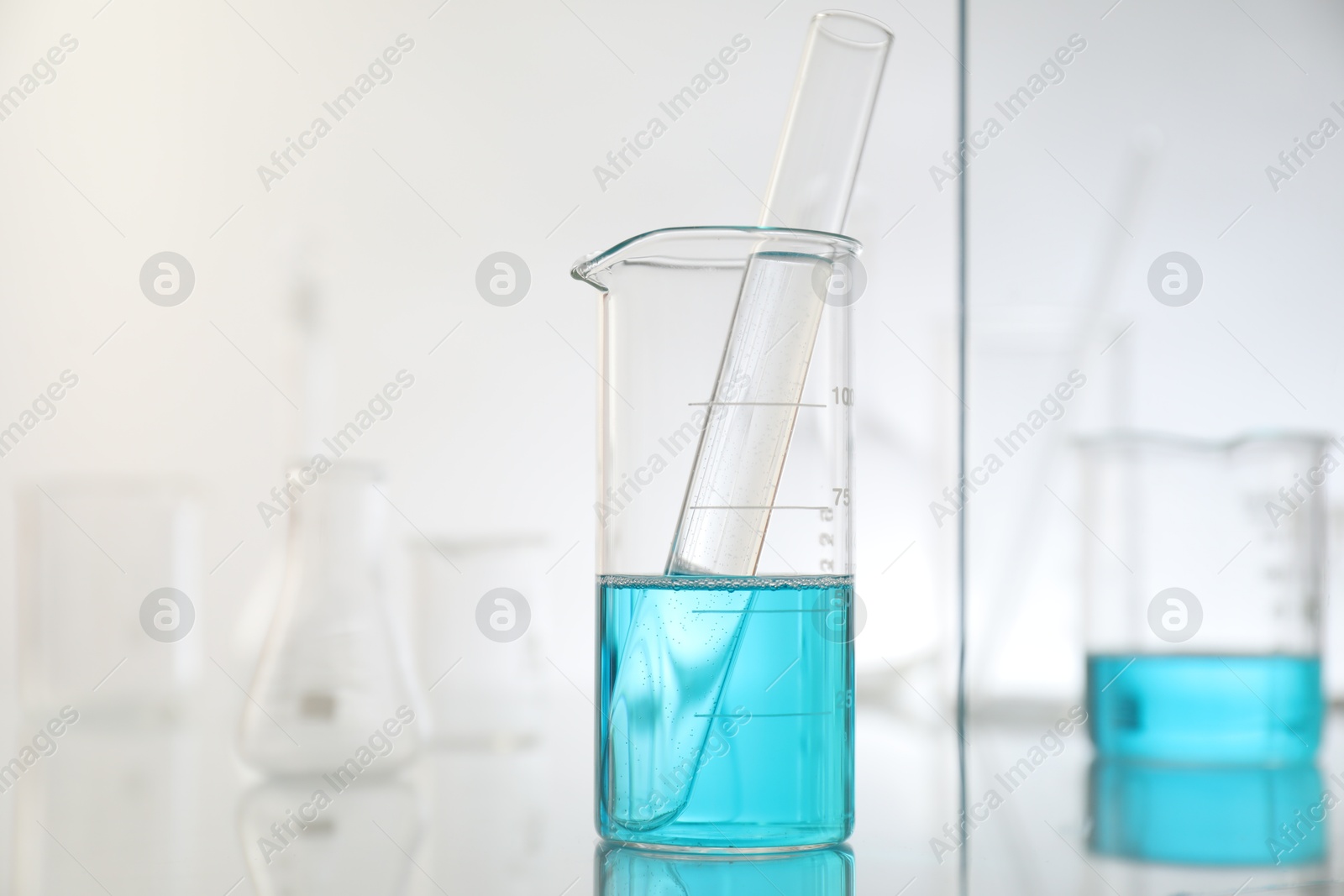 Photo of Laboratory glassware on mirror surface against light background