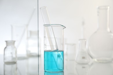 Photo of Laboratory glassware on mirror surface against light background