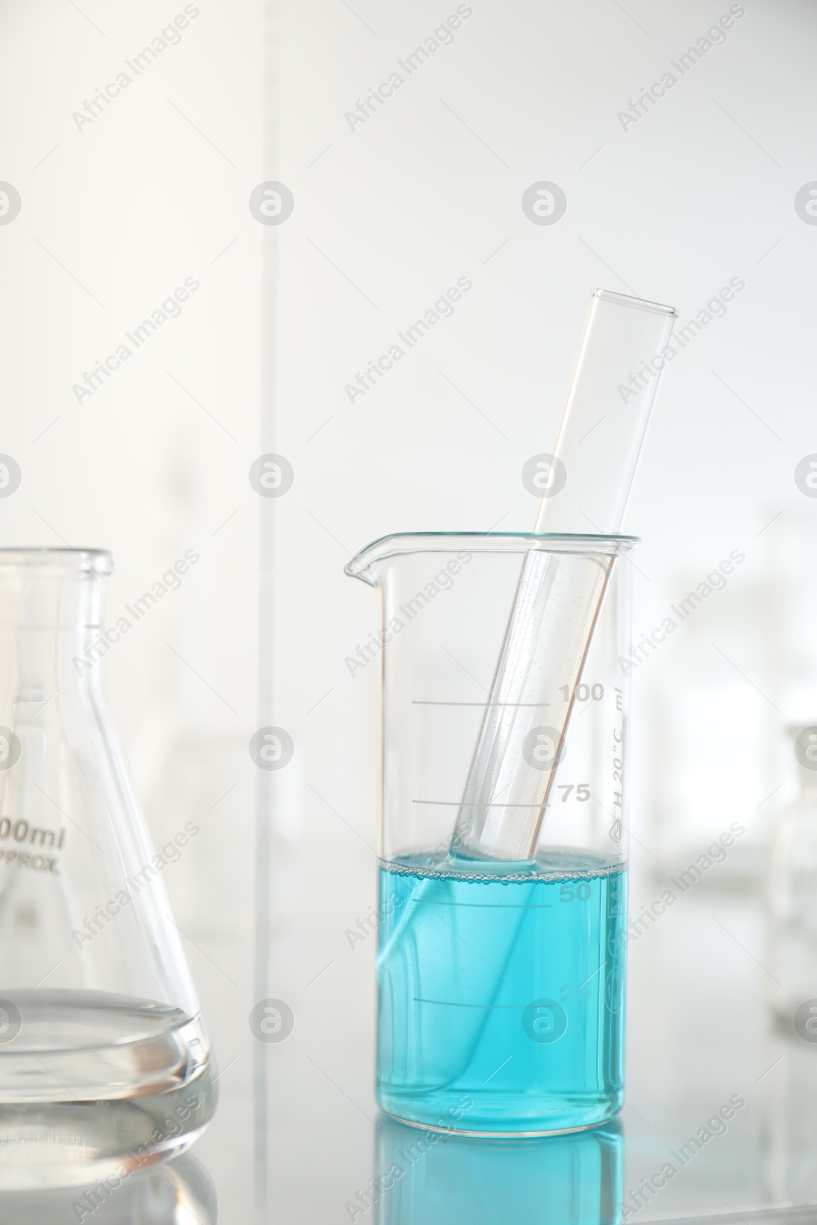 Photo of Laboratory glassware on mirror surface against light background