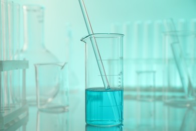 Photo of Laboratory glassware on mirror surface against turquoise background