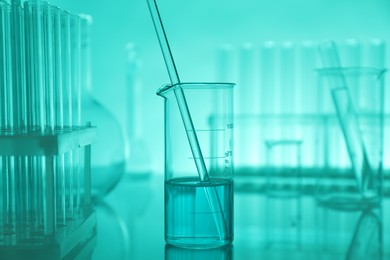 Photo of Laboratory glassware on mirror surface against turquoise background