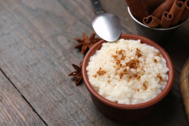 Photo of Tasty rice pudding with cinnamon served on wooden table, closeup. Space for text