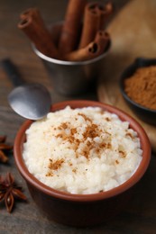 Photo of Tasty rice pudding with cinnamon served on wooden table, closeup