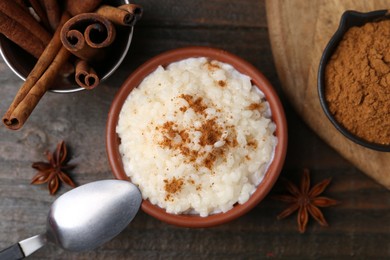 Photo of Tasty rice pudding with cinnamon served on wooden table, flat lay