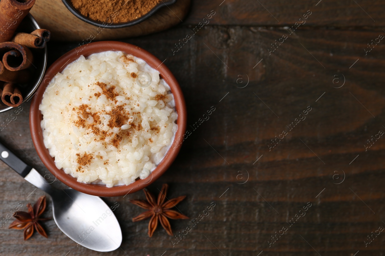 Photo of Tasty rice pudding with cinnamon served on wooden table, flat lay. Space for text