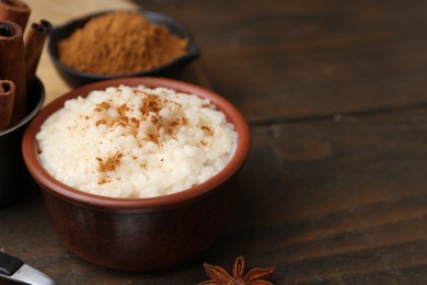 Photo of Tasty rice pudding with cinnamon served on wooden table, closeup. Space for text