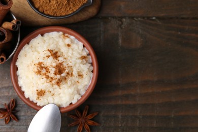 Photo of Tasty rice pudding with cinnamon served on wooden table, flat lay. Space for text