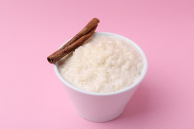 Photo of Tasty rice pudding with cinnamon on pink background, closeup