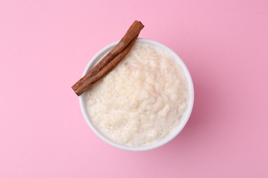 Photo of Tasty rice pudding with cinnamon on pink background, top view