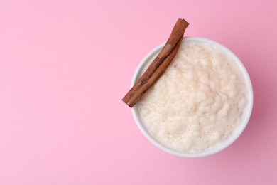 Photo of Tasty rice pudding with cinnamon on pink background, top view. Space for text